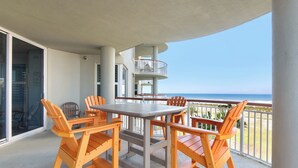 Un balcó amb taula i cadires, vista a l'oceà, i un edifici amb diversos balcons.