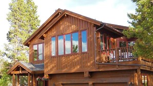 Une maison en bois à deux étages, dotée d’un balcon, d’un porche et d’un garage.