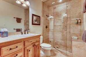 Une salle de bain avec un meuble-lavabo en bois, un lavabo, des toilettes et une douche à parois de verre.