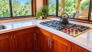 A kitchen with wooden cabinets, a stainless steel stove, and a window with a view of trees.