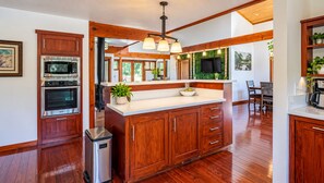 A kitchen with wooden cabinets, stainless steel appliances, a white countertop, and a dining area with a table and chairs.