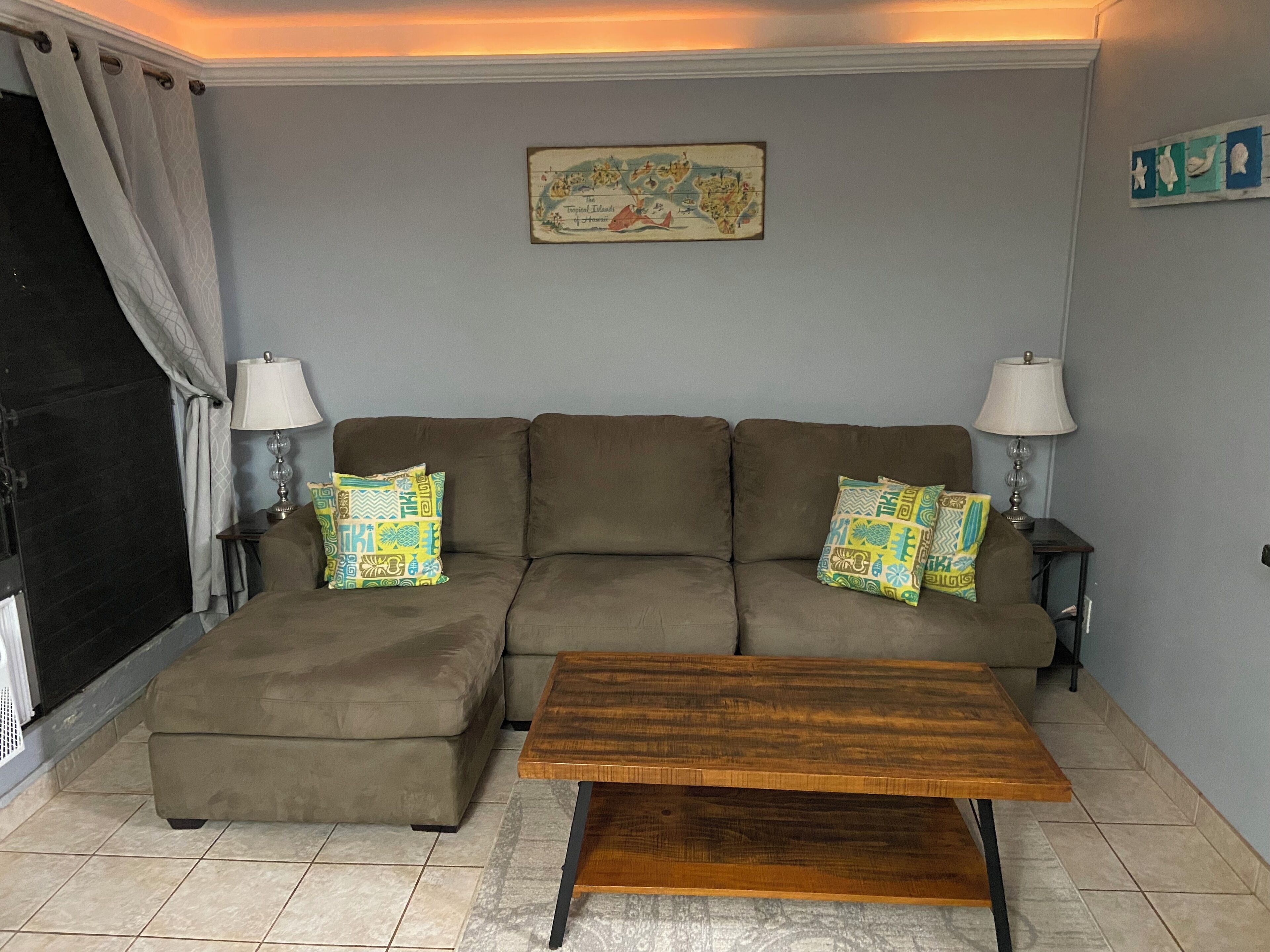 A living room with a sofa set, a coffee table, two lamps, and a wall map.