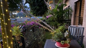 Un balcón con una mesa, plantas en macetas y guirnaldas de luces.