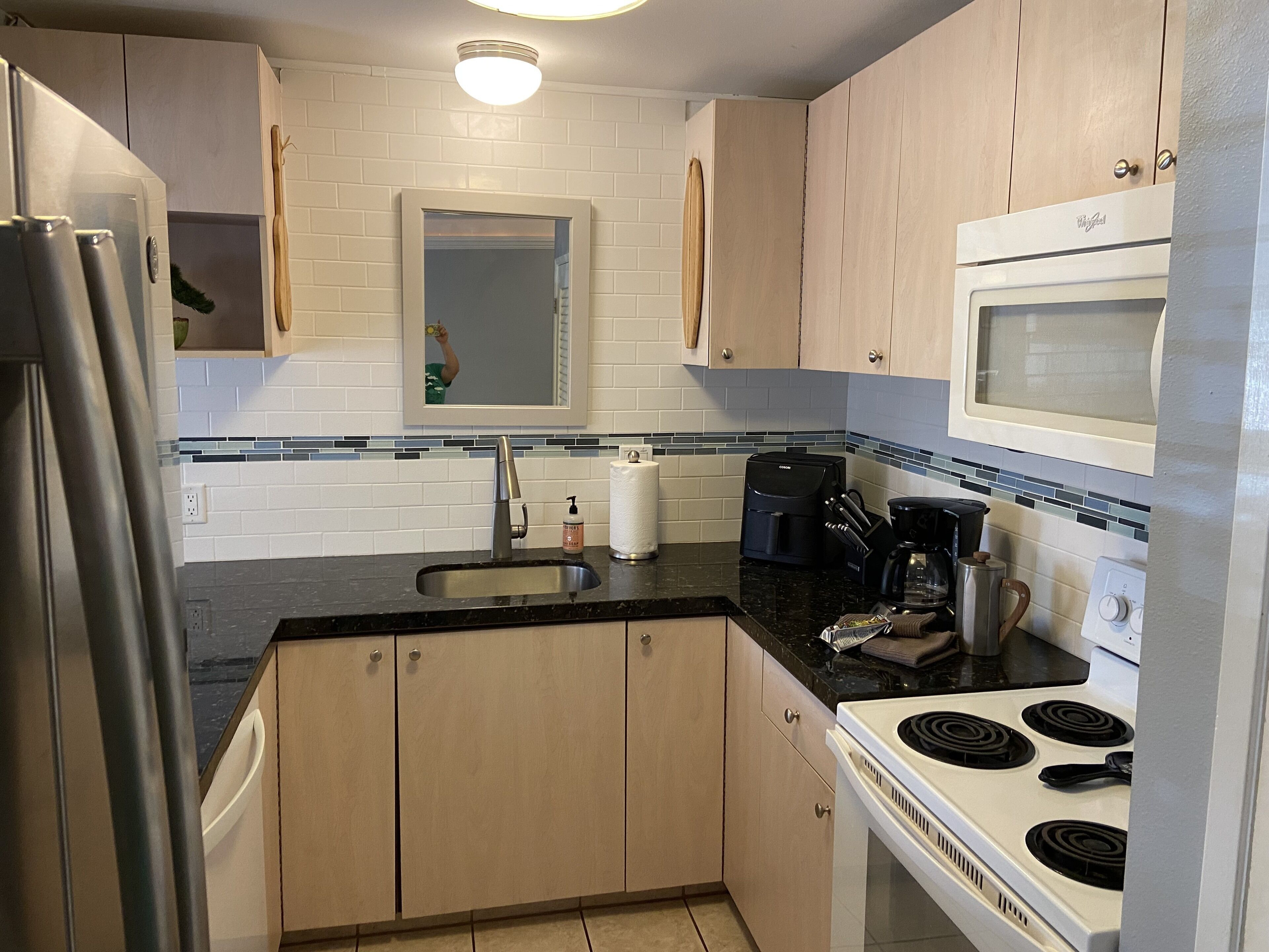 A kitchen with a refrigerator, stove, microwave, sink, and coffee maker.