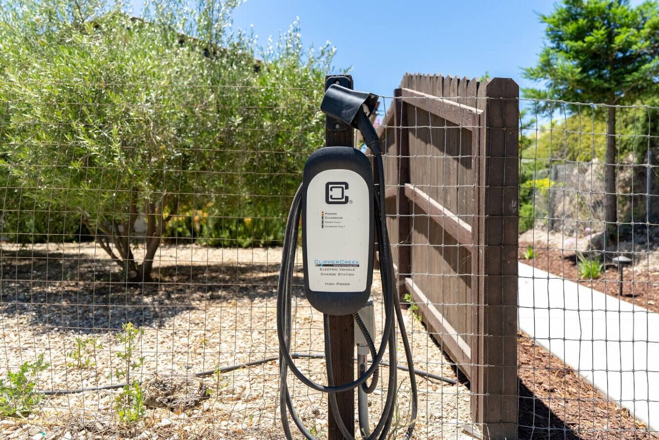A solar panel charging station with a label indicating it is for electric vehicles, connected to a fence.
