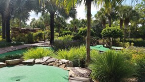 A golf course with a putting green, surrounded by lush greenery and palm trees. - Ultimate Orlando Adventure: Orange Lake Resort - Disney, Universal, Sea World! (Kissimmee)