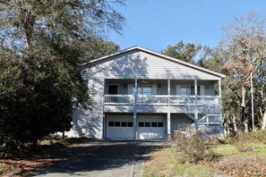 Stunning two-story residence with a central entrance, garage doors, and a balcony with columns.
