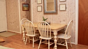 A dining area with a wooden table and four chairs, framed pictures on the wall, and a starfish decoration. - Perfect for multi-family gatherings! (Oak Island)