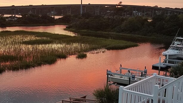 Vista al río con un muelle de madera y un pabellón blanco.