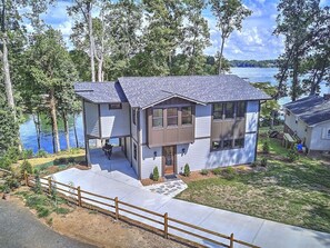 Enjoy a serene lakeside retreat with a two-story house, front porch, and covered patio.