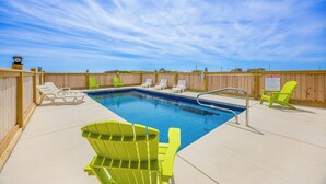 A swimming pool with lounge chairs and a wooden fence.