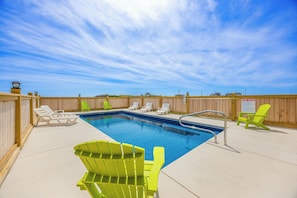 A swimming pool with lounge chairs and a wooden fence.
