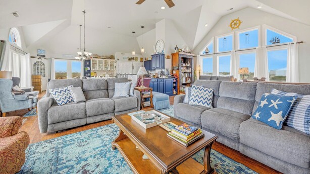 A spacious living room with two grey sofas, a wooden coffee table, and a large window with a view.