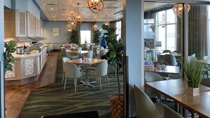 Un restaurante con bufé, varias zonas de estar y vistas de la ciudad.