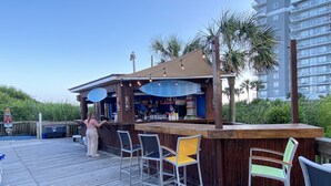 Una terraza de madera con zona de bar, que incluye una barra y taburetes.