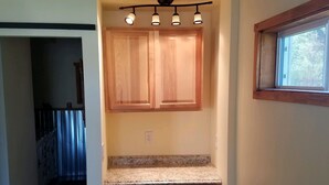 Una cocina compacta con armarios de madera, lavavajillas integrado y una ventana sobre el fregadero.