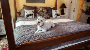Una cama con colchón acolchado, cabecera de madera y un perro acostado en la cama.