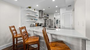 A modern kitchen with white cabinetry, a central island, and wooden chairs.