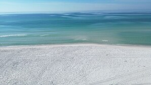 A beach with clear blue water and a sandy shore.