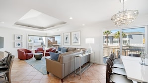 A spacious living area with a modern sofa, red chairs, a dining table, and a balcony with a view of palm trees. - LOCATION!!!  7 Bedrooms - VIEW - Steps to Sand+Ocean+Pier+Downtown PISMO BEACH! (Pismo Beach)