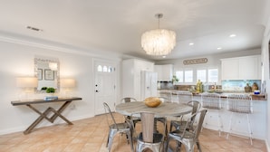 A modern kitchen with white cabinetry, a round dining table, and a chandelier. - LOCATION!!!  7 Bedrooms - VIEW - Steps to Sand+Ocean+Pier+Downtown PISMO BEACH! (Pismo Beach)