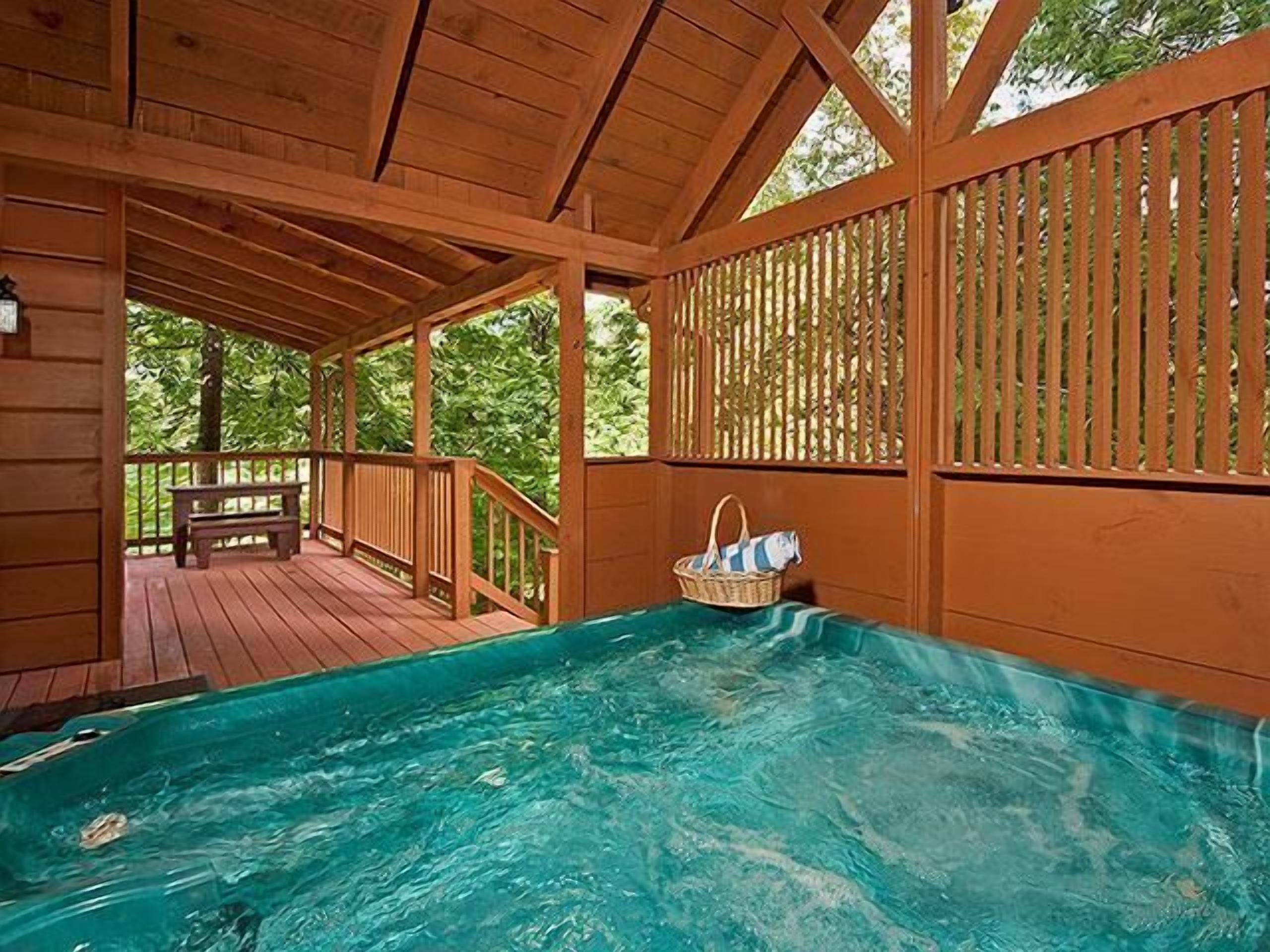 Une terrasse en bois avec un jacuzzi et un banc.