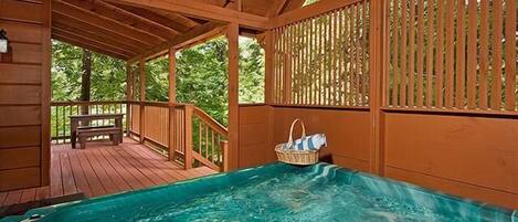 A wooden deck with a hot tub and a bench.