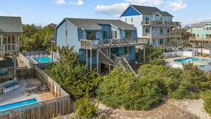 A coastal property with multiple buildings, including a main house with a balcony and a separate pool area. - Oceanfront, Dog Friendly Home with Private Pool, Hot Tub, and Beach Sunrises! (Salvo)