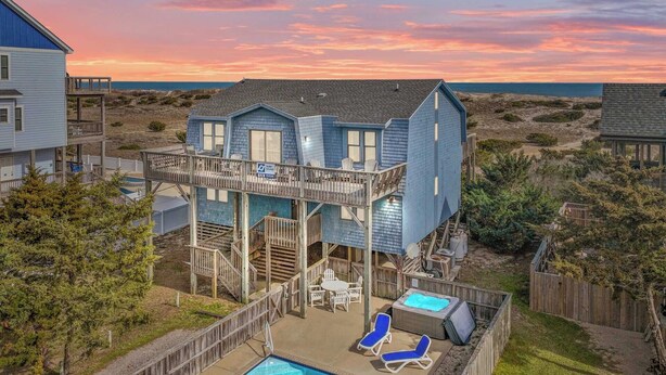 A two-story house with a pool, deck chairs, and a view of the ocean at sunset. - Oceanfront, Dog Friendly Home with Private Pool, Hot Tub, and Beach Sunrises! (Salvo)