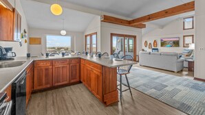 A spacious kitchen with wooden cabinets, a large island, and a view of the beach. - Oceanfront, Dog Friendly Home with Private Pool, Hot Tub, and Beach Sunrises! (Salvo)
