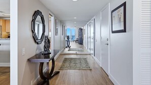 Un couloir avec un plancher en bois, un miroir, un tapis et des tableaux encadrés accrochés aux murs.