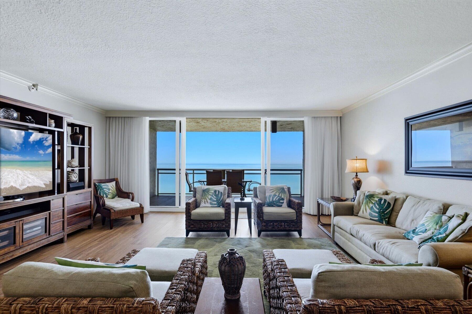 Ein Hotelzimmer mit Balkon, Fernseher, Korbmöbeln und Meerblick.
