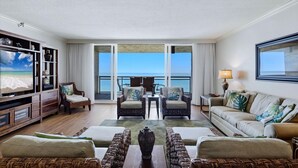 Une chambre d’hôtel avec balcon, télévision, mobilier en osier et vue sur l’océan.