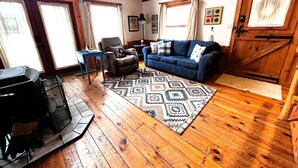 Un accogliente soggiorno con parquet, un divano blu, una poltrona e un tappeto.