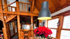 Un interno rustico in legno con un lungo tavolo da pranzo, panche e un lampadario.