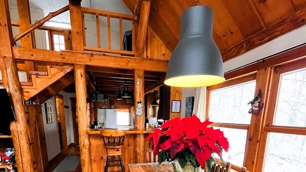 Un interno rustico in legno con un lungo tavolo da pranzo, panche e un lampadario.