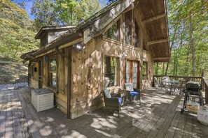 A wooden cabin with a deck, built-in seating, and a grill area. - A couple's get-away in the woods. (Nelsonville)