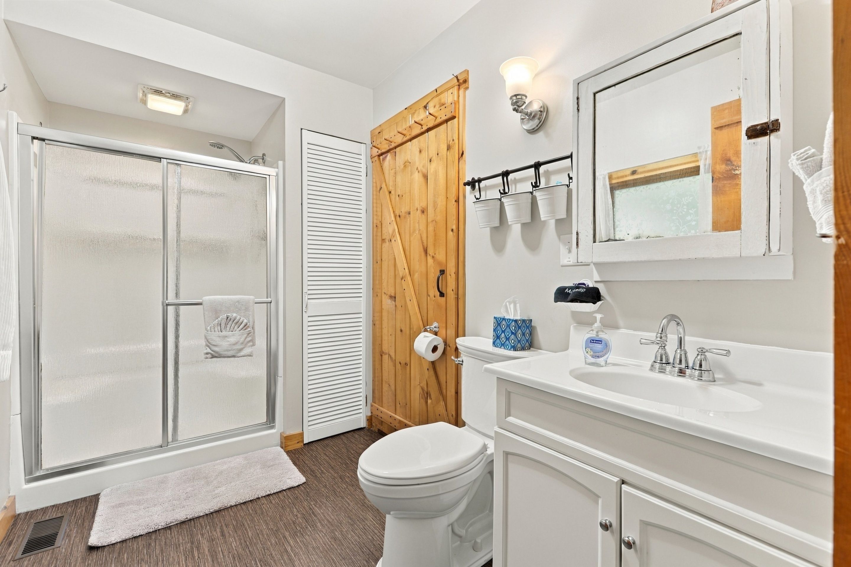 Een badkamer met een douche, toilet, wastafel en een spiegel.