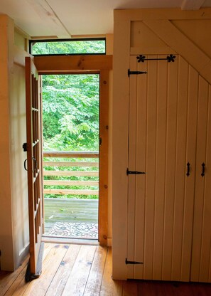 Una habitación con puerta de madera que da a un balcón con vistas a zonas verdes.