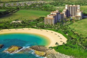 Un resort con playa, varios edificios de gran altura y un campo de golf.