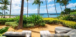 Un área de descanso en la playa con tumbonas, palmeras y vistas al océano.