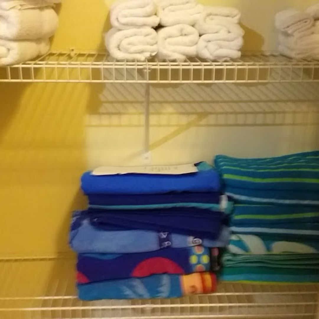 A storage area with neatly folded towels and folded clothes on shelves.