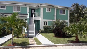A two-story building with a central staircase, a balcony on the upper floor, and a well-maintained lawn with palm trees. - Cedar Pine Villas - Quiet, 'Luxury & Comfort Rolled Into One' (Nassau)