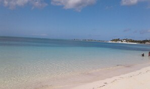 Une plage à l’eau turquoise et limpide, bordée d’un rivage sablonneux.