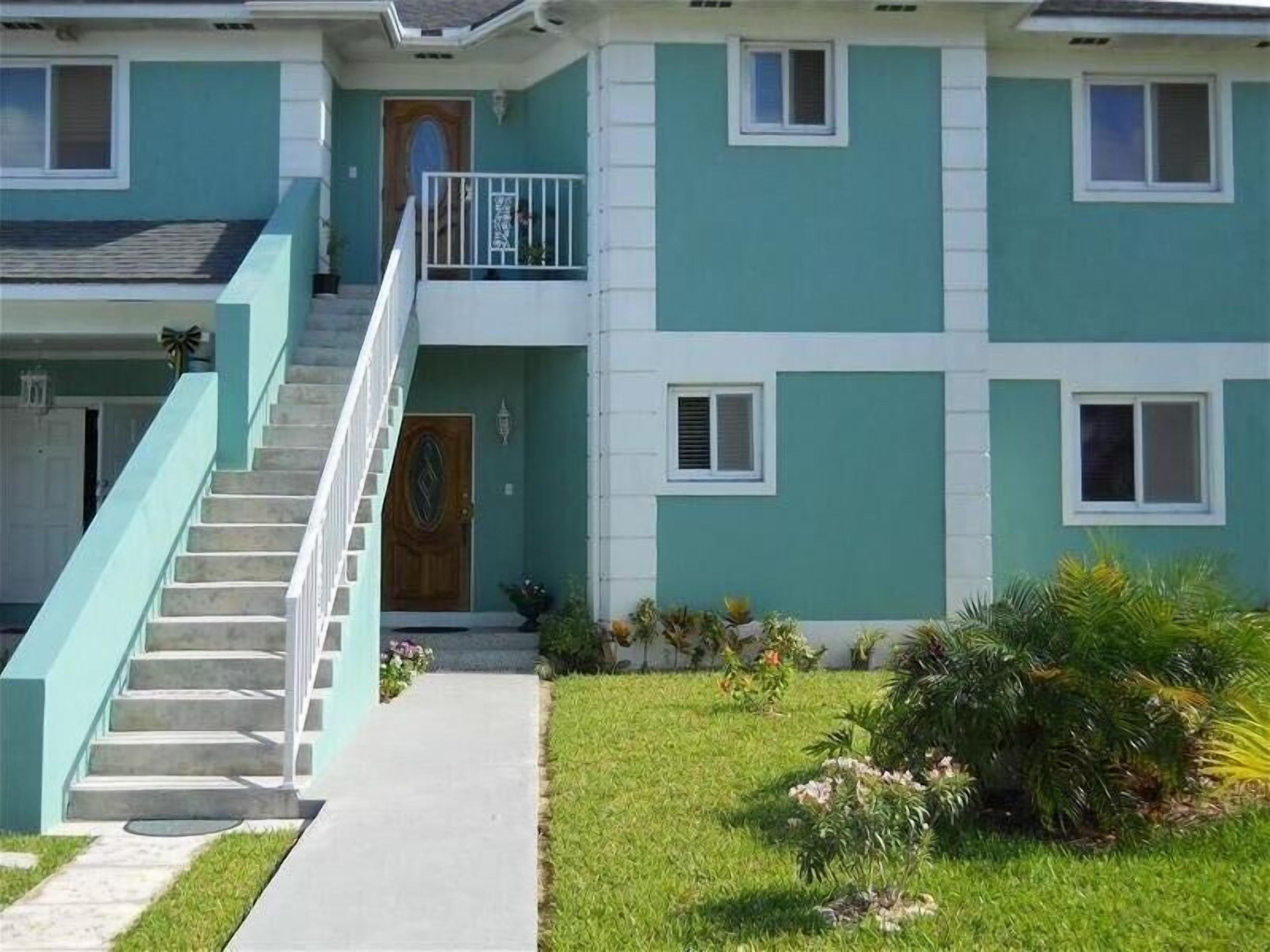 Un edificio a due piani con portico anteriore, una scala e un piccolo giardino.