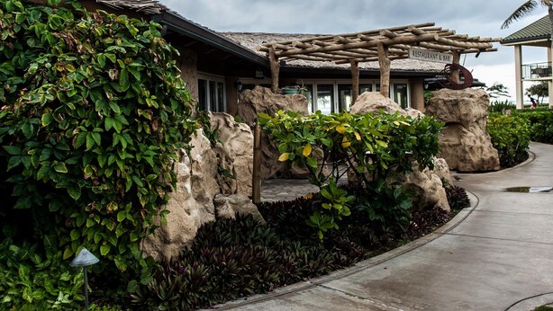 A building with a stone facade, a covered outdoor area, and a pathway leading to it. -  Luxury Ocean Front Property!  Ocean& pool view.  B204  (Kapaa)