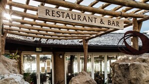 A wooden pergola with a sign reading "RESTAURANT & BAR" above a stone pathway leading to a building with glass doors. -  Luxury Ocean Front Property!  Ocean& pool view.  B204  (Kapaa)
