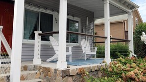 A house with a porch, white Adirondack chairs, and a stone wall. - Jamestown: Cozy Coastal Cottage in town near beaches & Newport, dogs OK! (Jamestown)
