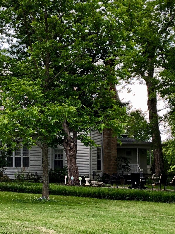 A house with a front porch, a lawn, and a tree in the foreground.