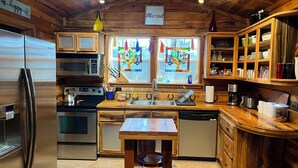 A kitchen with wooden cabinets, stainless steel appliances, a wooden table, and a window with stained glass. - Unique farm guest house close to Chattanooga, TN- great for families and dogs (Chickamauga)